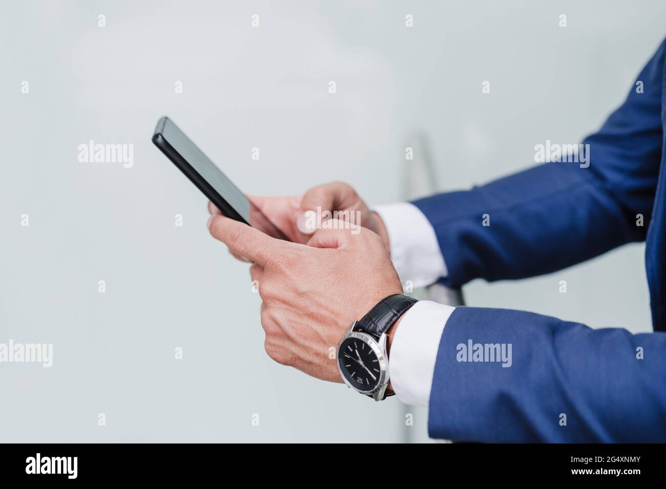 Businessman using mobile phone while leaning on railing Stock Photo