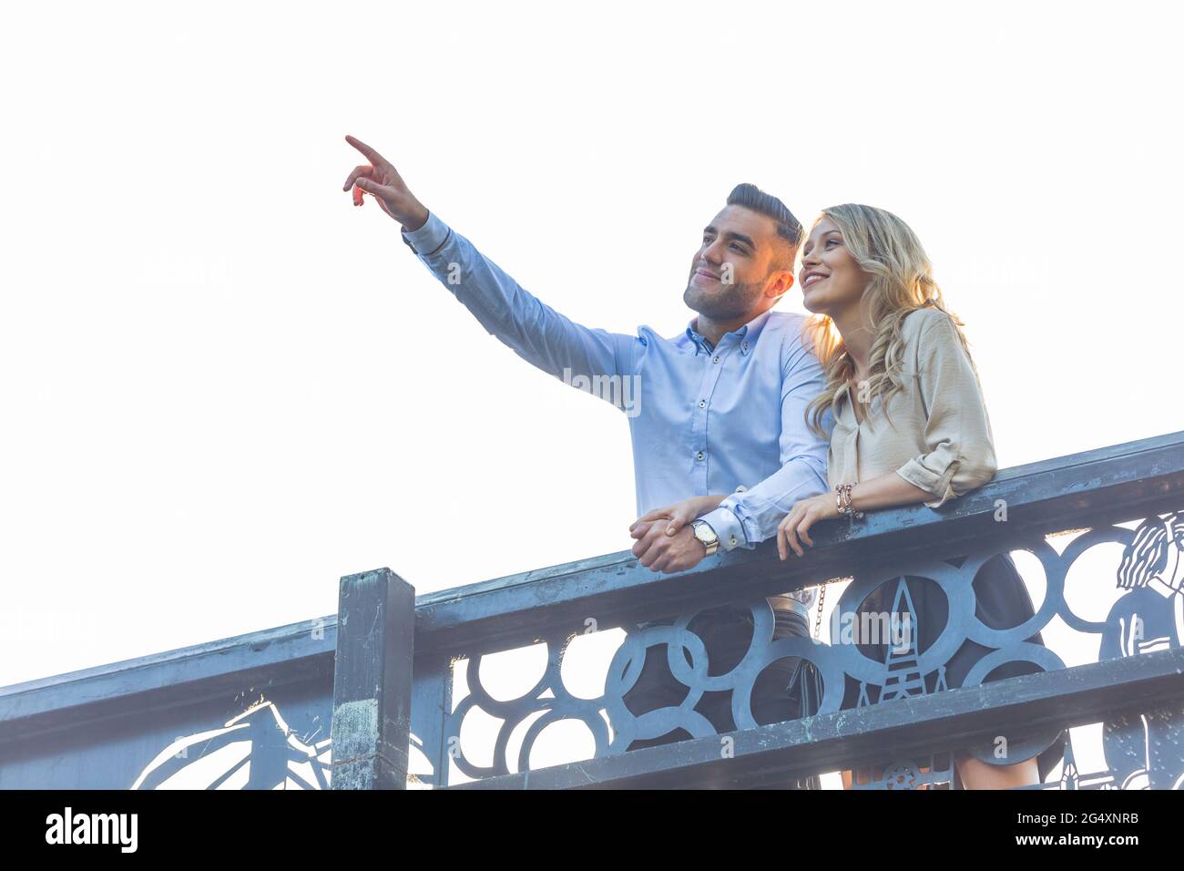 Man pointing while standing at railing with girlfriend Stock Photo