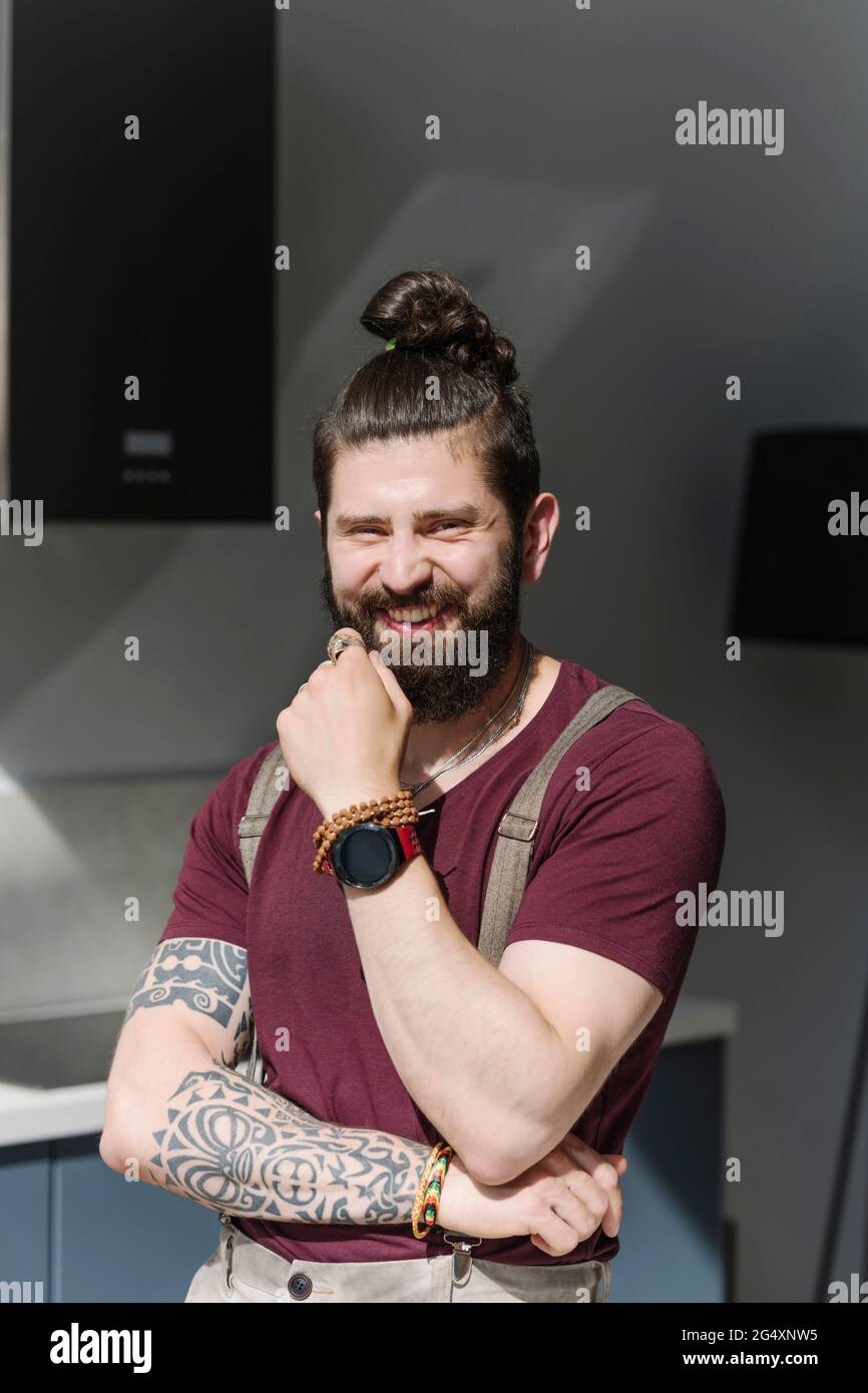 Bearded man smiling while standing at home Stock Photo