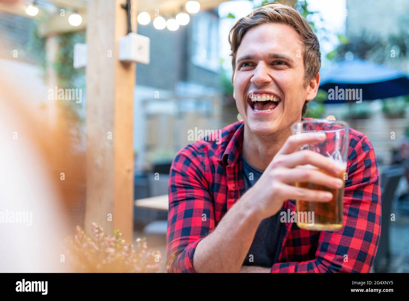 Man laughing while holding beer glass at pub Stock Photo