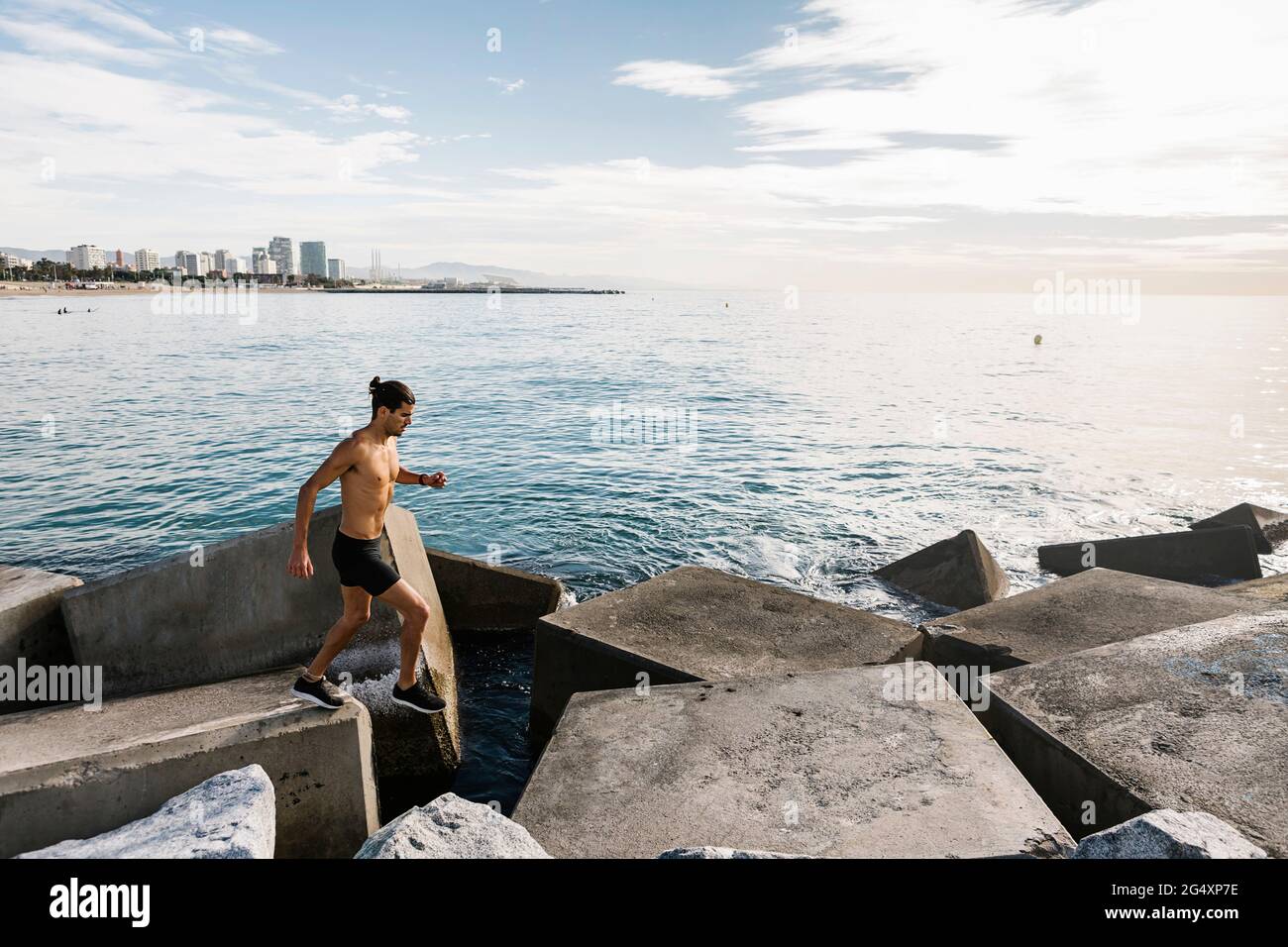 Sportsman running on rocks by sea Stock Photo