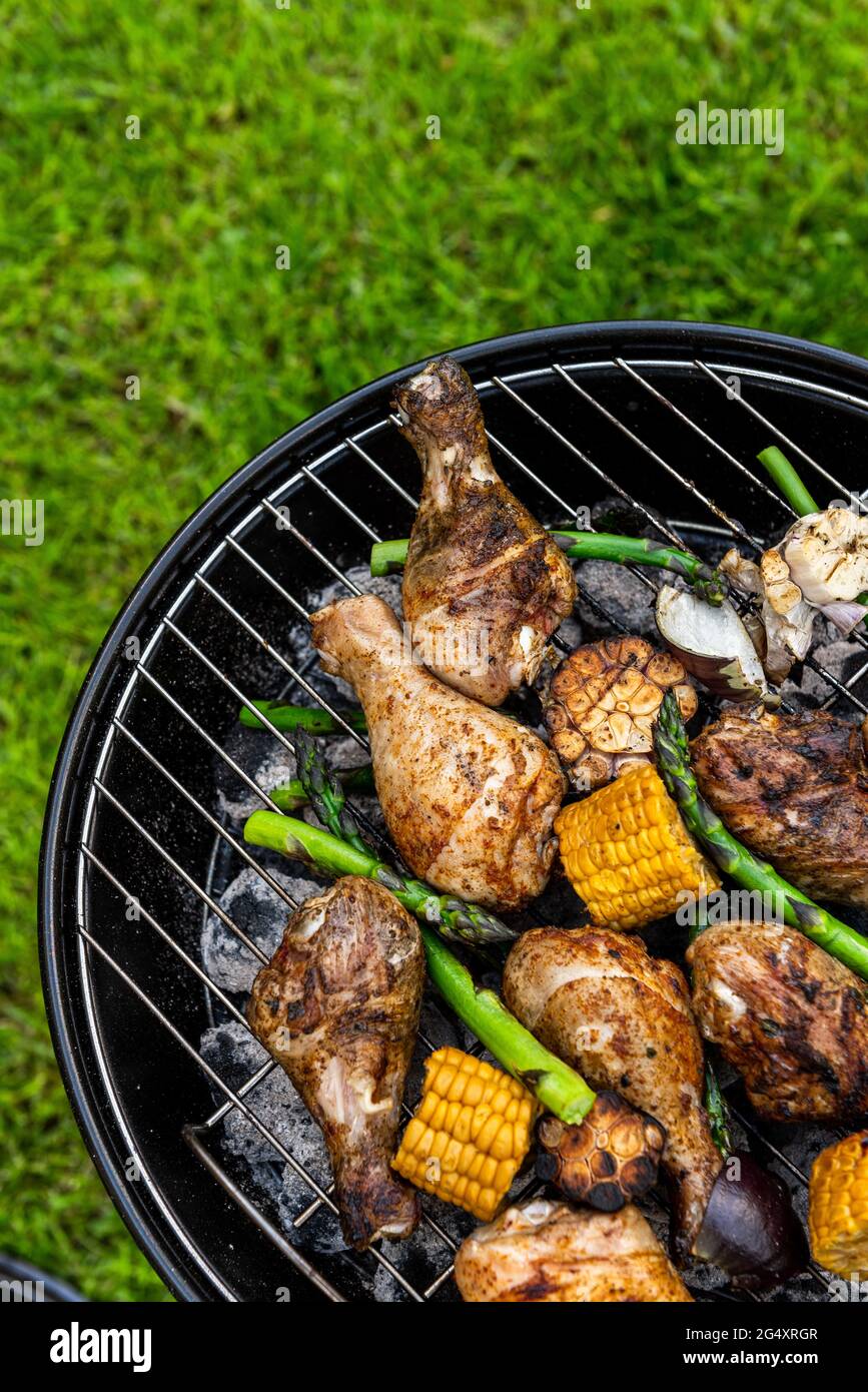 Chicken Drumsticks Legs Grilled on Charcoal BBQ in Backyard Garden at