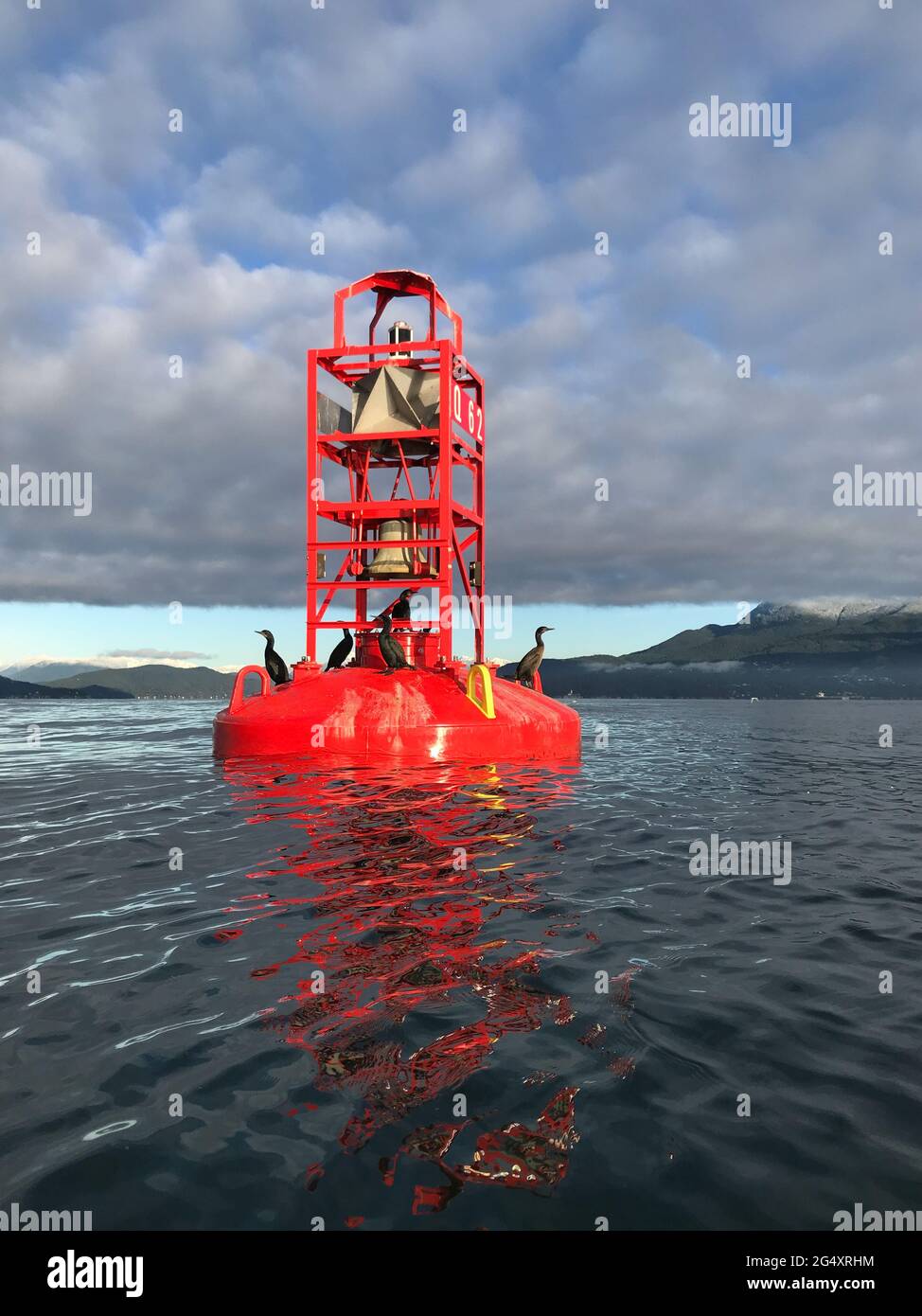 Red bell buoy shipping channel marker near shore in ocean Stock Photo