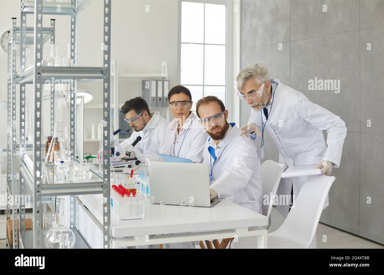 Scientist group discussing looking at laptop screen working at laboratory Stock Photo