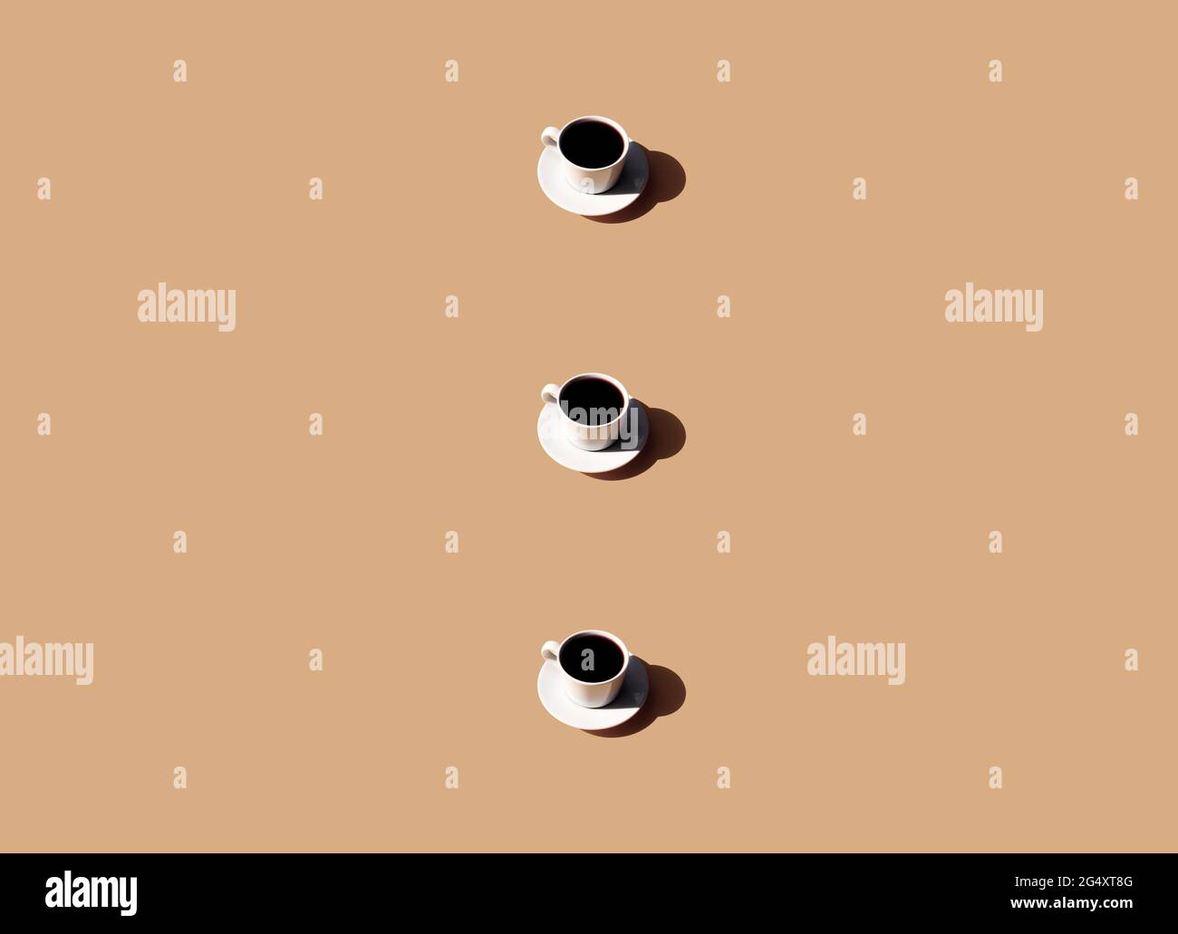 Pattern of white cup and saucer plate of black espresso coffee top view with shadow of sun on beige terracotta background. High quality photo Stock Photo