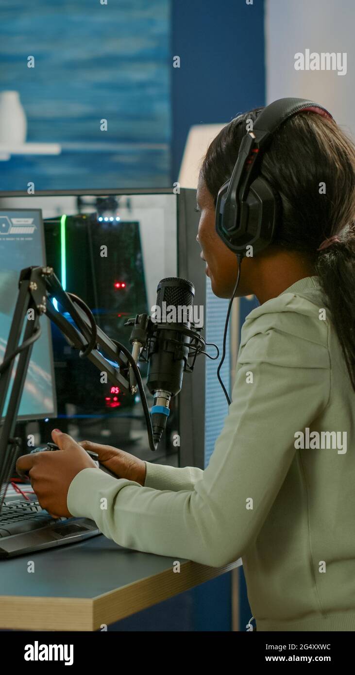 Black woman streamer playing space shooter videogames with joystick ...