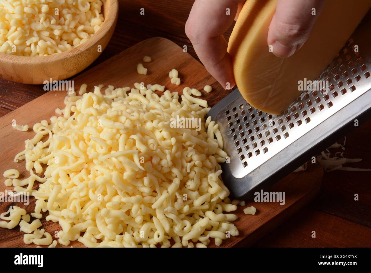 https://c8.alamy.com/comp/2G4XYYX/man-grating-cheese-on-small-wooden-board-grated-cheese-for-cooking-on-a-cutting-board-on-a-wooden-background-2G4XYYX.jpg