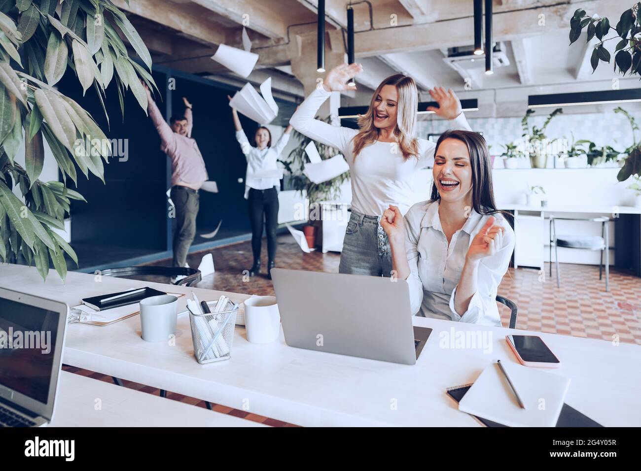 Two young happy businesswomen celebrating project success in office ...