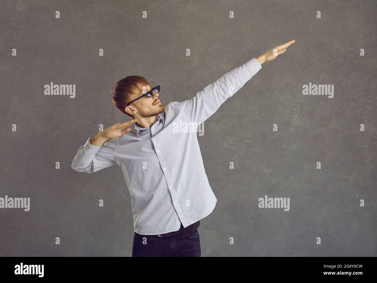 Young businessman in thug life glasses dancing dab against grey studio  background Stock Photo - Alamy