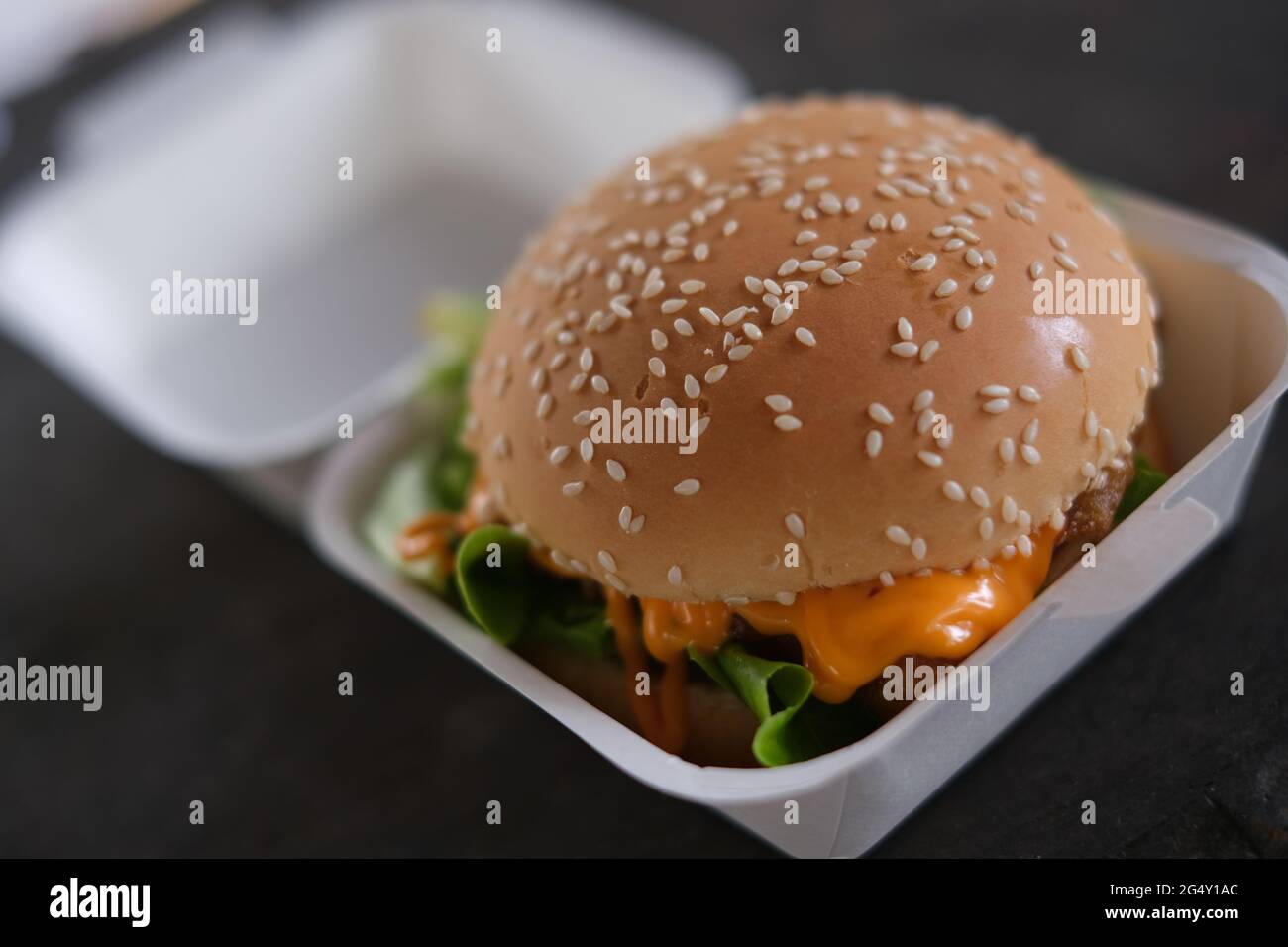 A big, good looking cheeseburger in a cardboard, ready to eat Stock Photo