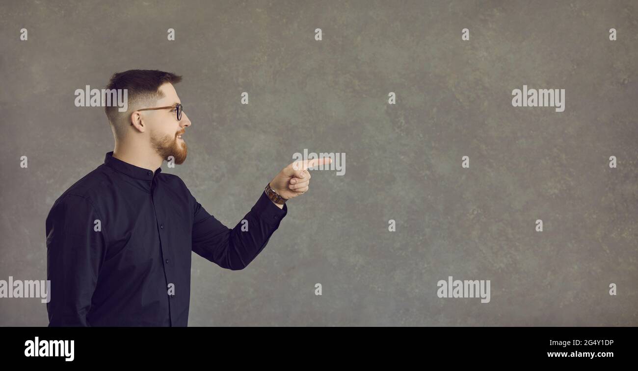 Young caucasian man in eyeglasses pointing aside to studio empty copy space Stock Photo