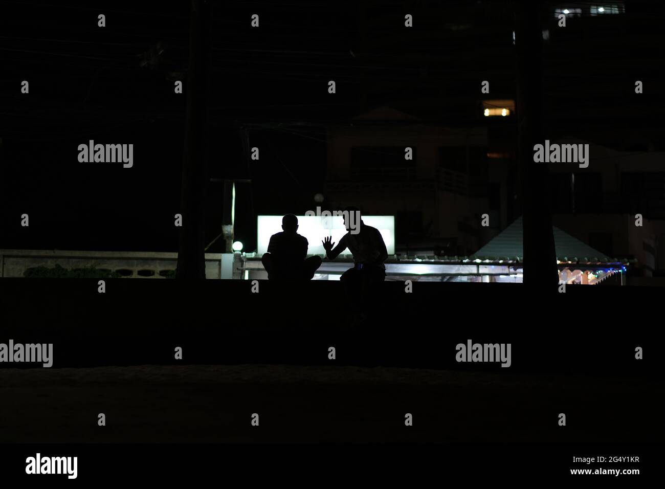 A dialogue of two men, visible only as silhouettes, with one hearing intrigued and another one gesturing Stock Photo