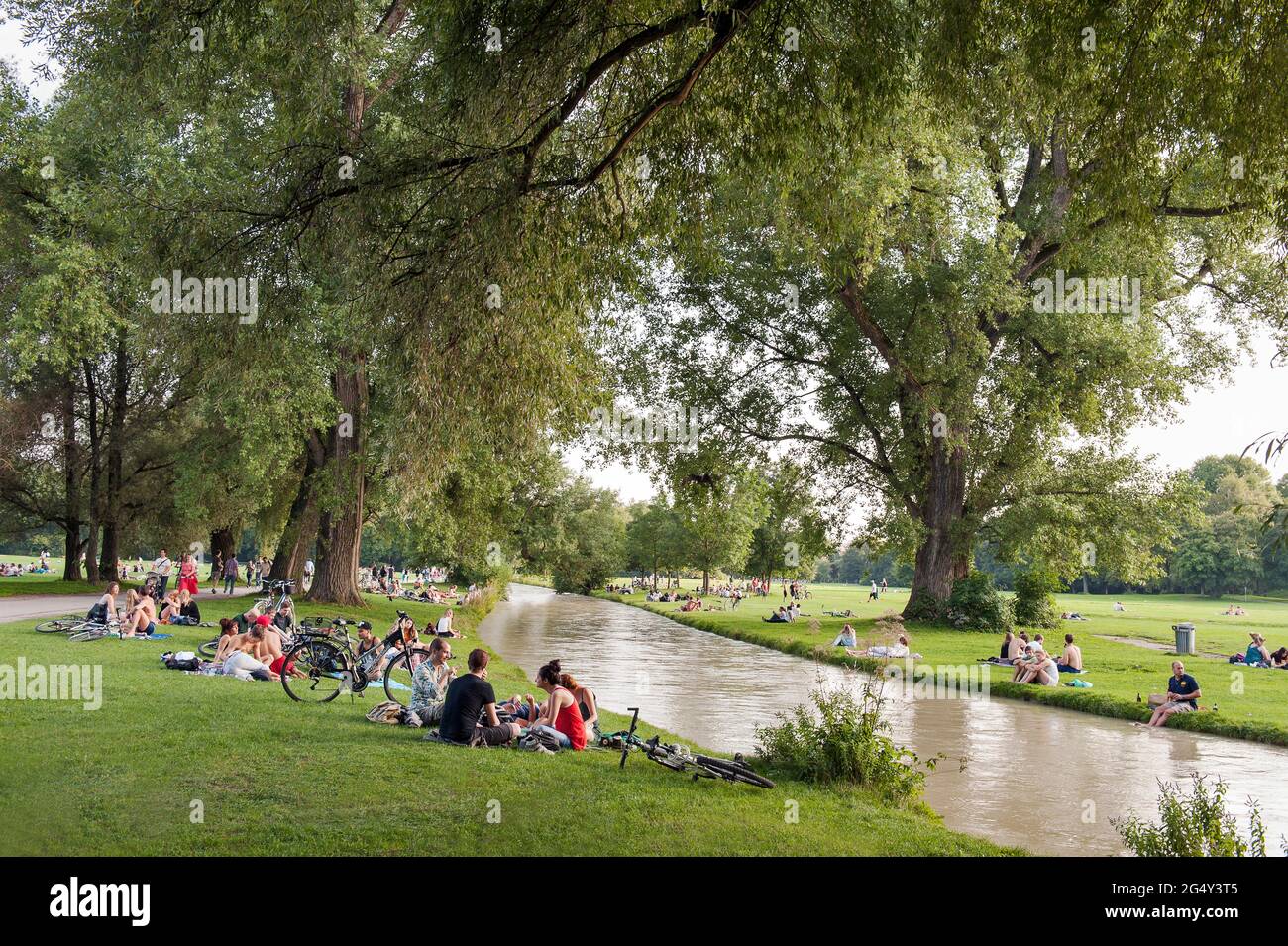 Munich - Bayen- Germany, June 11th, 2021: People who relax in the grass and do sports like cycling on the EIsbach. At the weekend, many went to the En Stock Photo