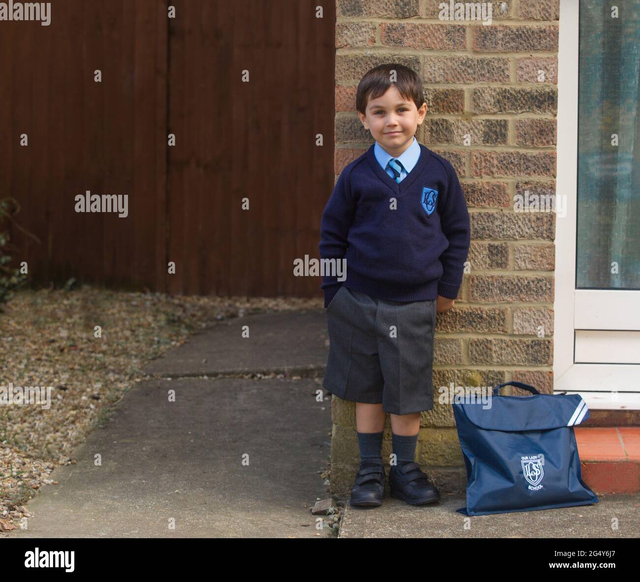 young boy posing in school uniform outside house Stock Photo