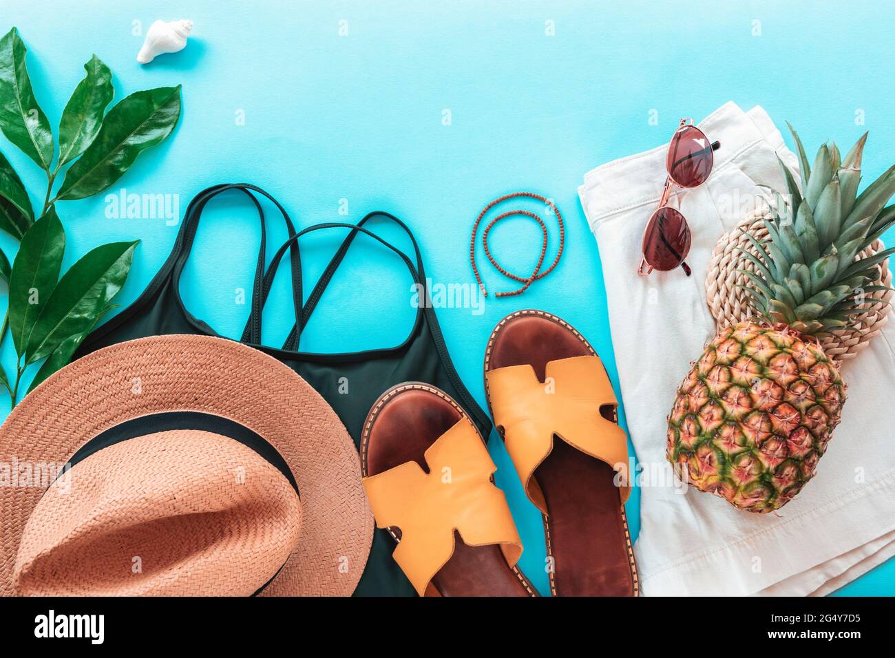 Women's summer clothes, accessories, slippers and pineapple on blue background. Beauty, fashion, summer vacation concept. Top view, flat lay, copy spa Stock Photo