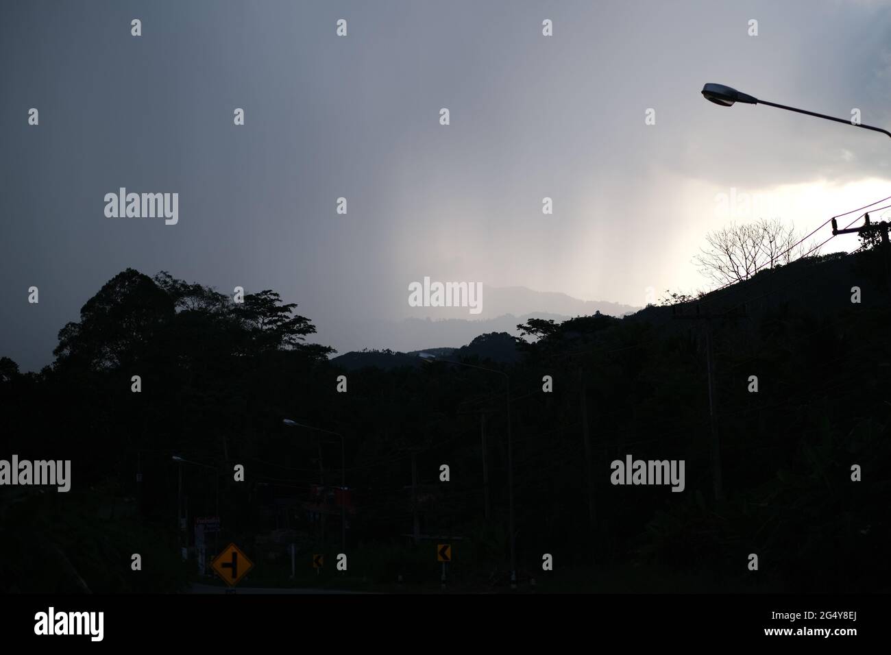 Incoming heavy rain over mountains, road signs and electric transmission line in a remote highland region of South Thailand Stock Photo