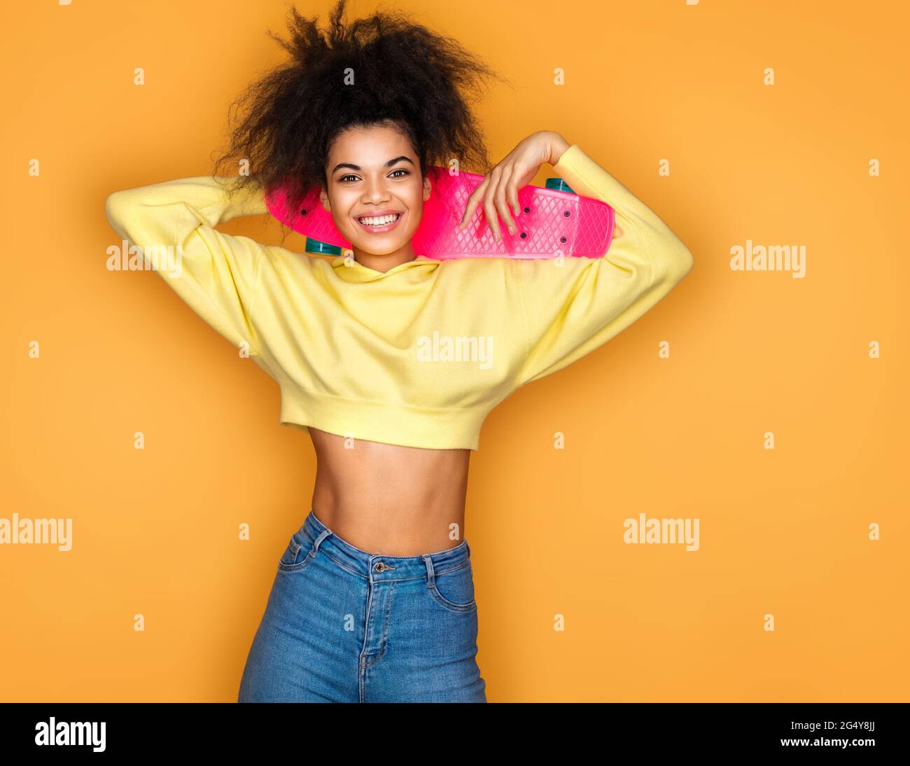 Cool girl with skateboard on yellow background Stock Photo