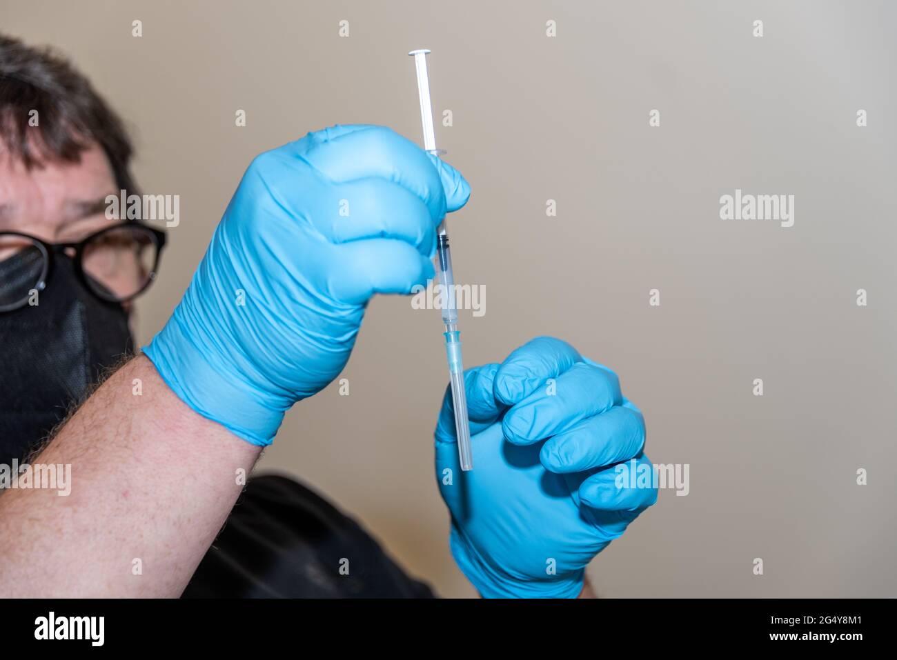 Aufziehen einer Impfdosis aus der Impfstoffampulle in die Injektionsspritze durchn einen Arzt Stock Photo