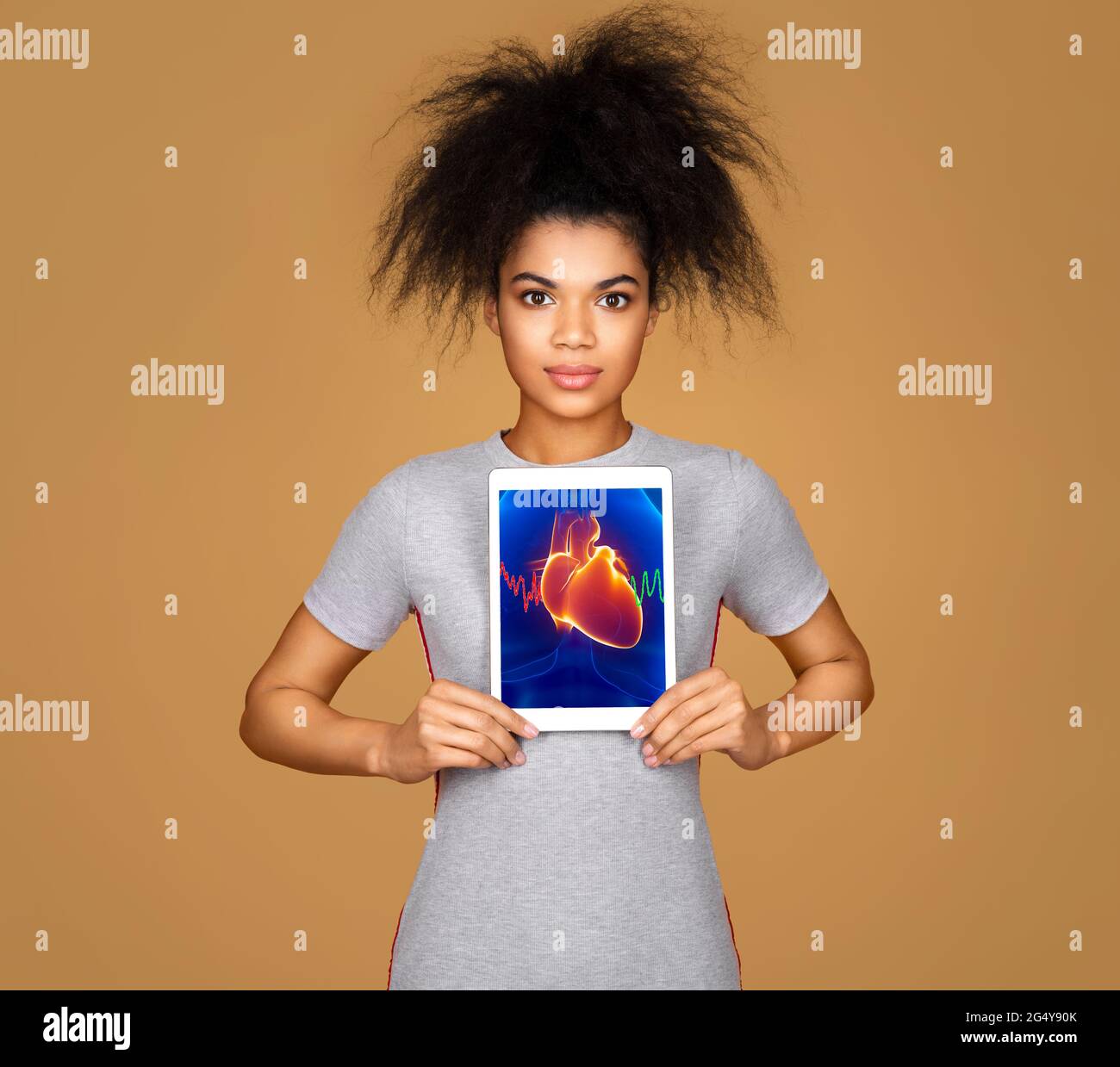 Girl shows the x-ray image of the heart. Photo of young girl with tablet in her hands on beige background. Medical concept Stock Photo