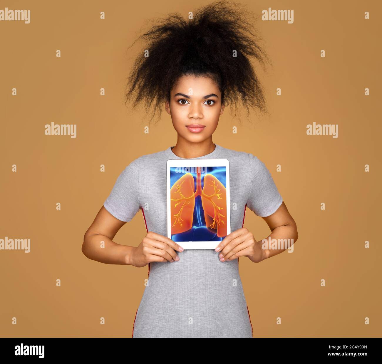 Girl shows the x-ray image of the lungs. Photo of young girl with tablet in her hands on beige background. Medical concept Stock Photo