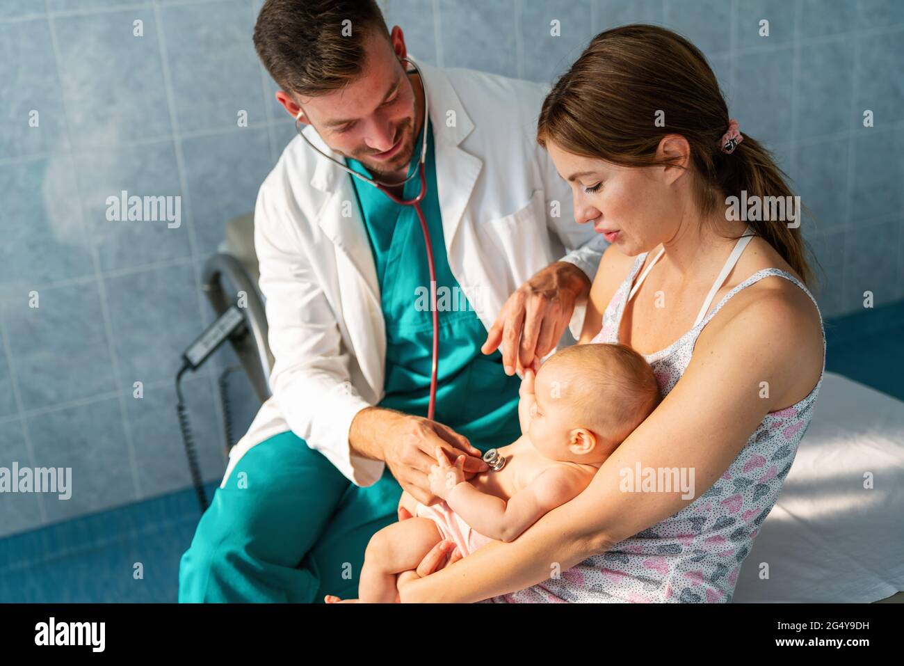 Pediatrician doctor examines baby with stethoscope checking heart beat