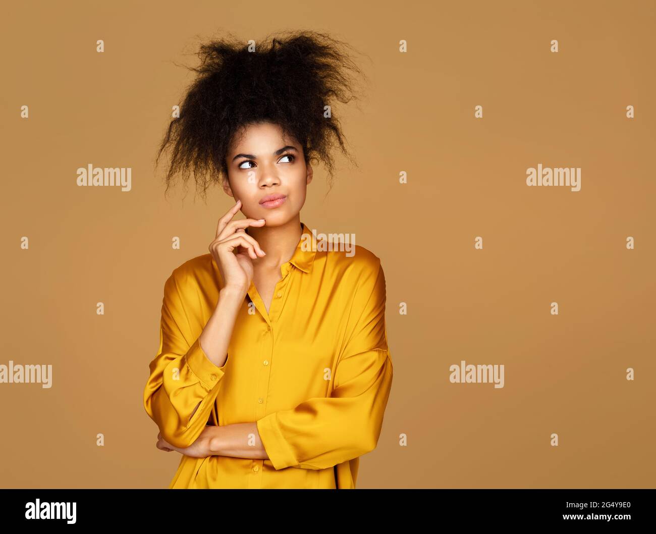 Thoughtful girl thinks about something, makes decision. Photo of african american girl on beige background Stock Photo
