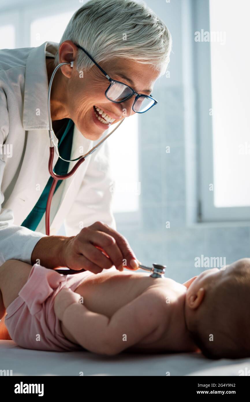 Pediatrician doctor examines baby with stethoscope checking heart beat