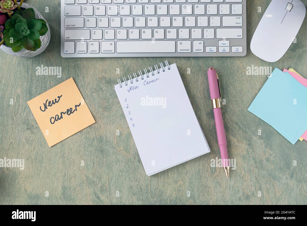 top view of the desktop with note with words NEW CAREER, empty notepad, pen, keyboard, cactus and mause on a wooden table. Business and finance concept. Flat lay Stock Photo