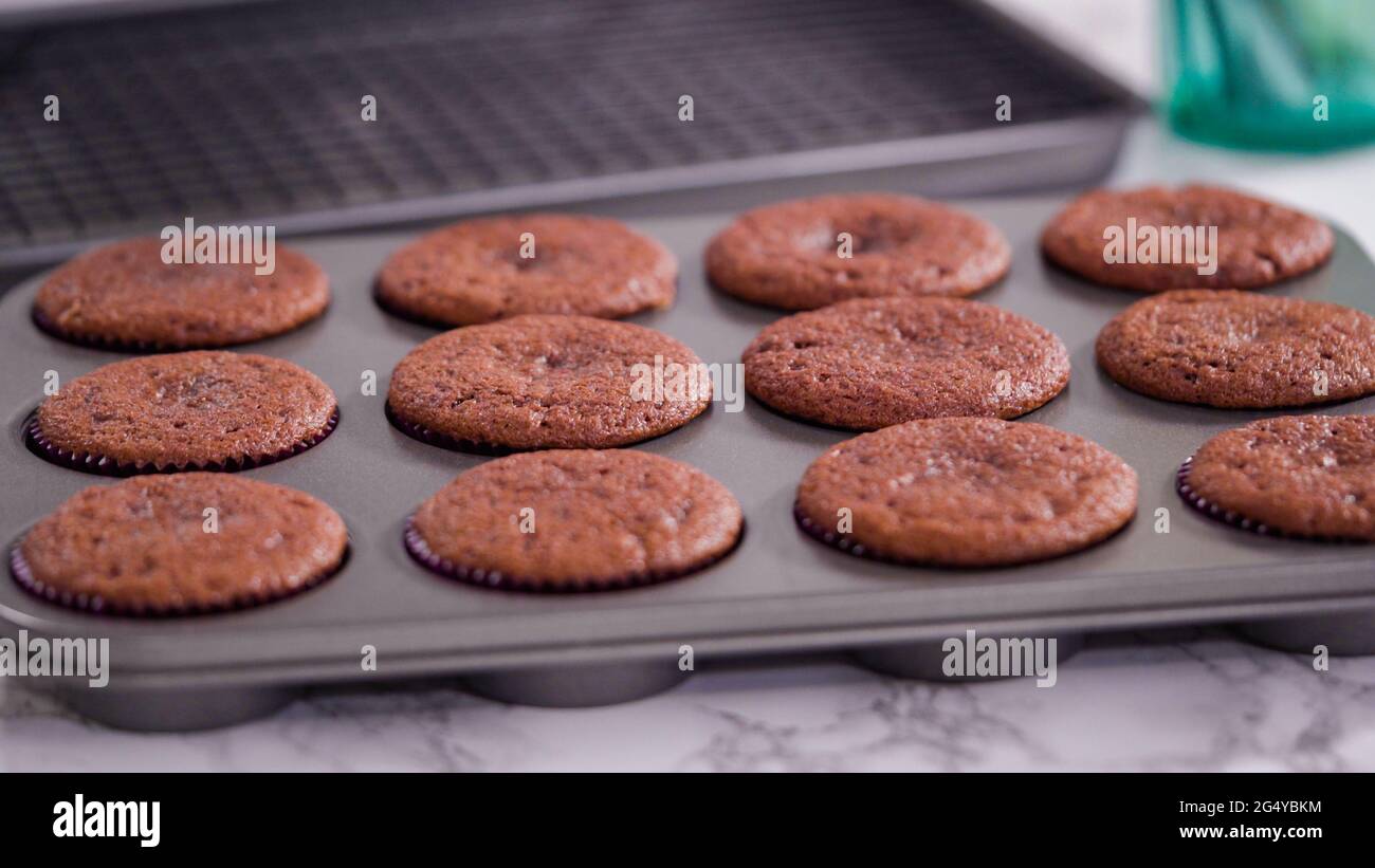 Step by step. Cooling red velvet cupcakes on a kitchen drying rack. Stock Photo