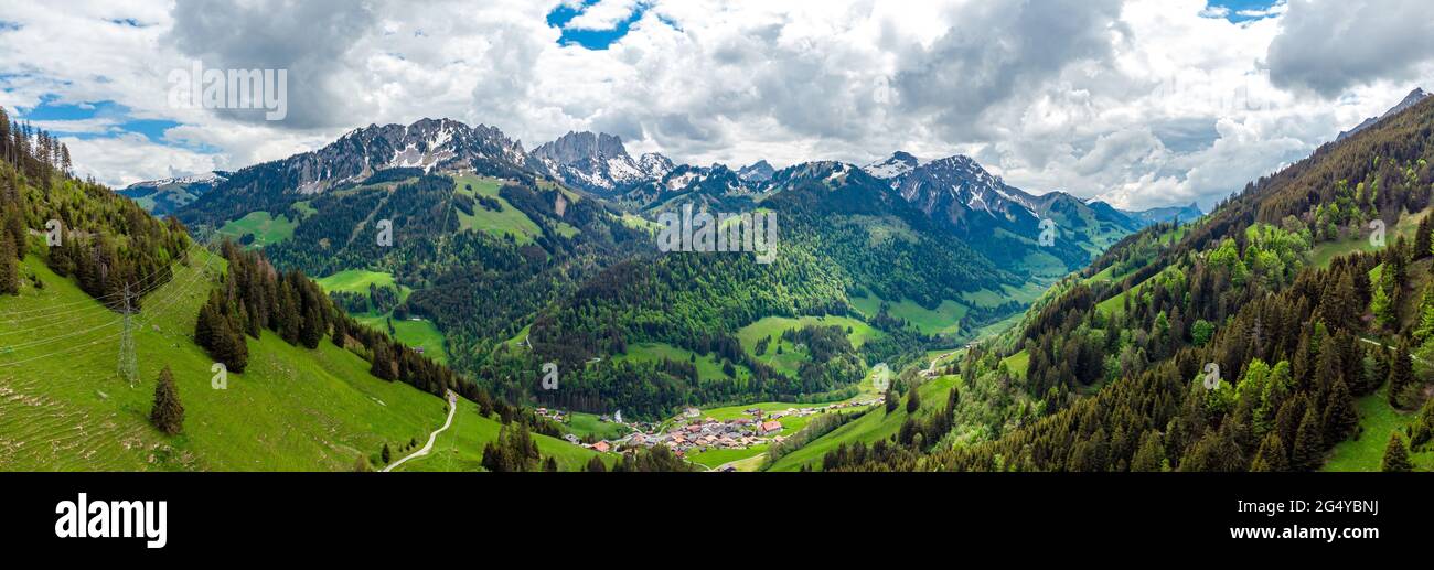 View on alps mountains, green fields, cloudy sky by Jaun,  Jaunpass. Canton Fribourg, Freiburg nearby Bulle, Bern, Thun. Good hiking tourist way. Swit Stock Photo