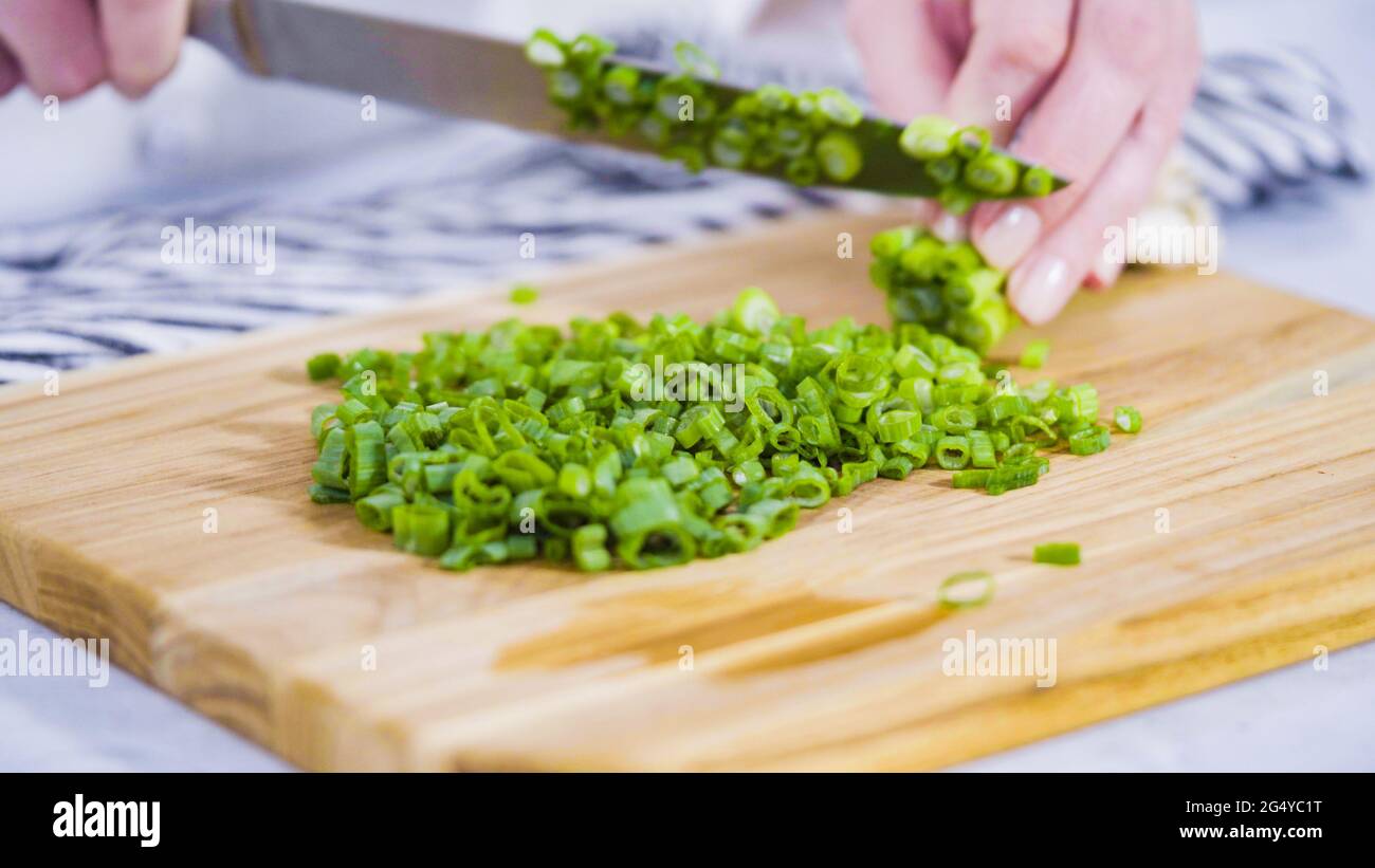 Step by step. Chopping organic green onions on a wood cutting board ...