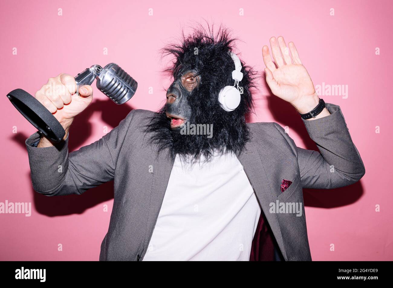 Gesture man with gorilla mask and headphones singing with microphone Stock Photo