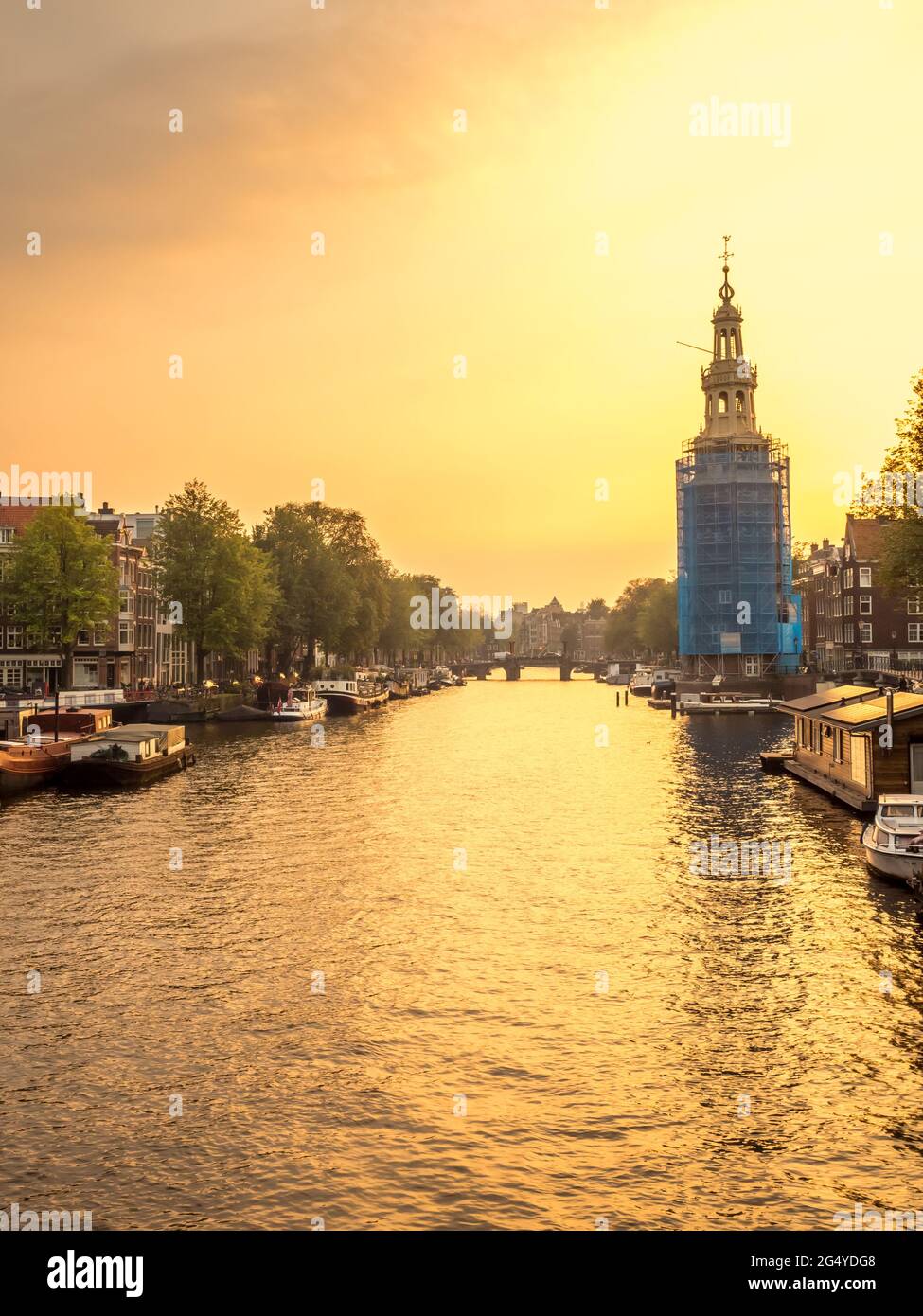 Constructed clock tower along canal in Amsterdam with evening light sky ...