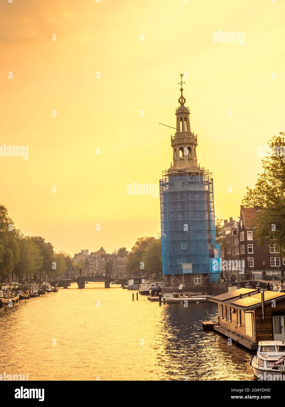 Constructed clock tower along canal in Amsterdam with evening light sky ...
