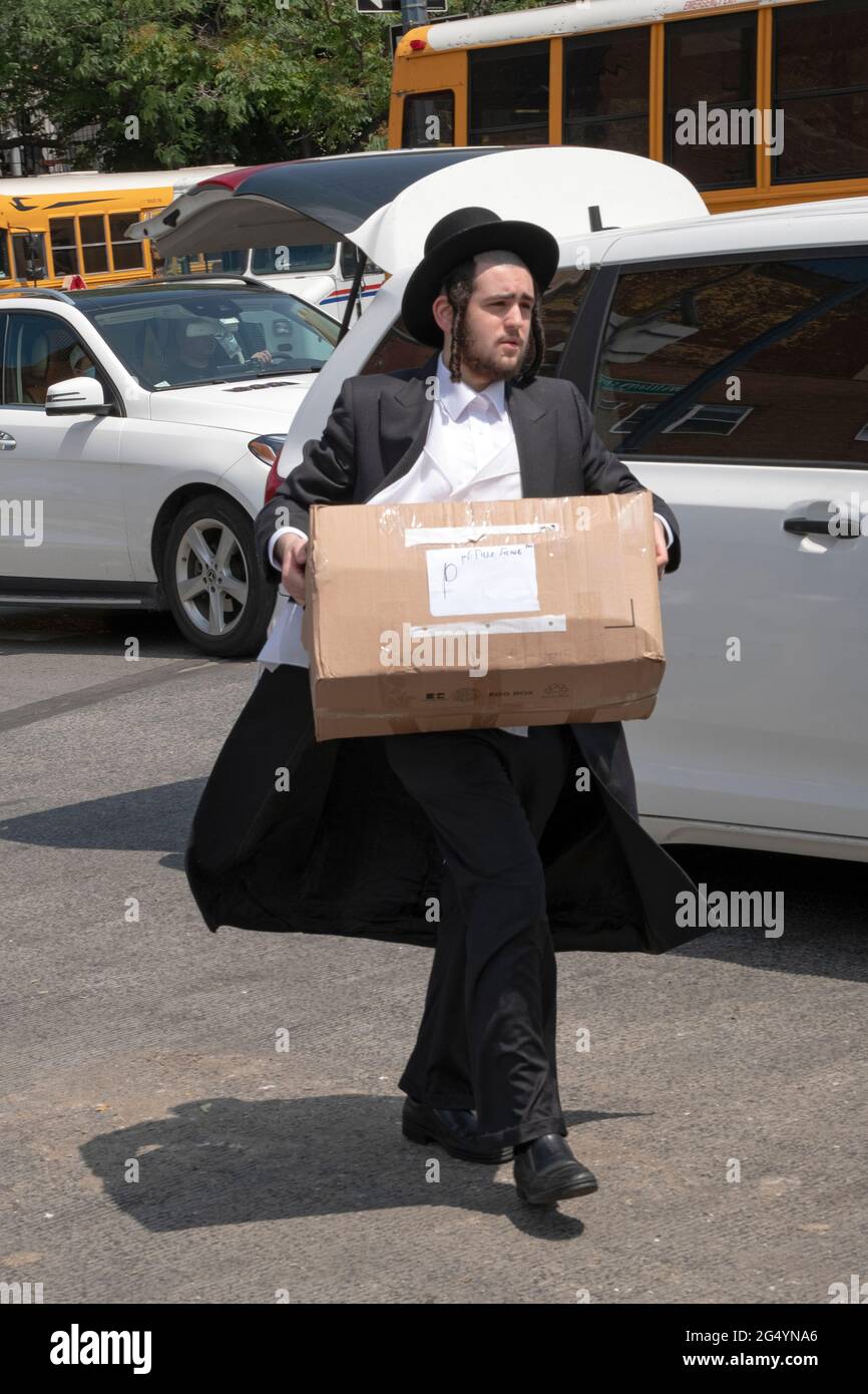 Orthodox Jewish men take packages of their sibling's summer items to be bused to the camp they'll be attending. In Williamsburg, Brooklyn, New York. Stock Photo