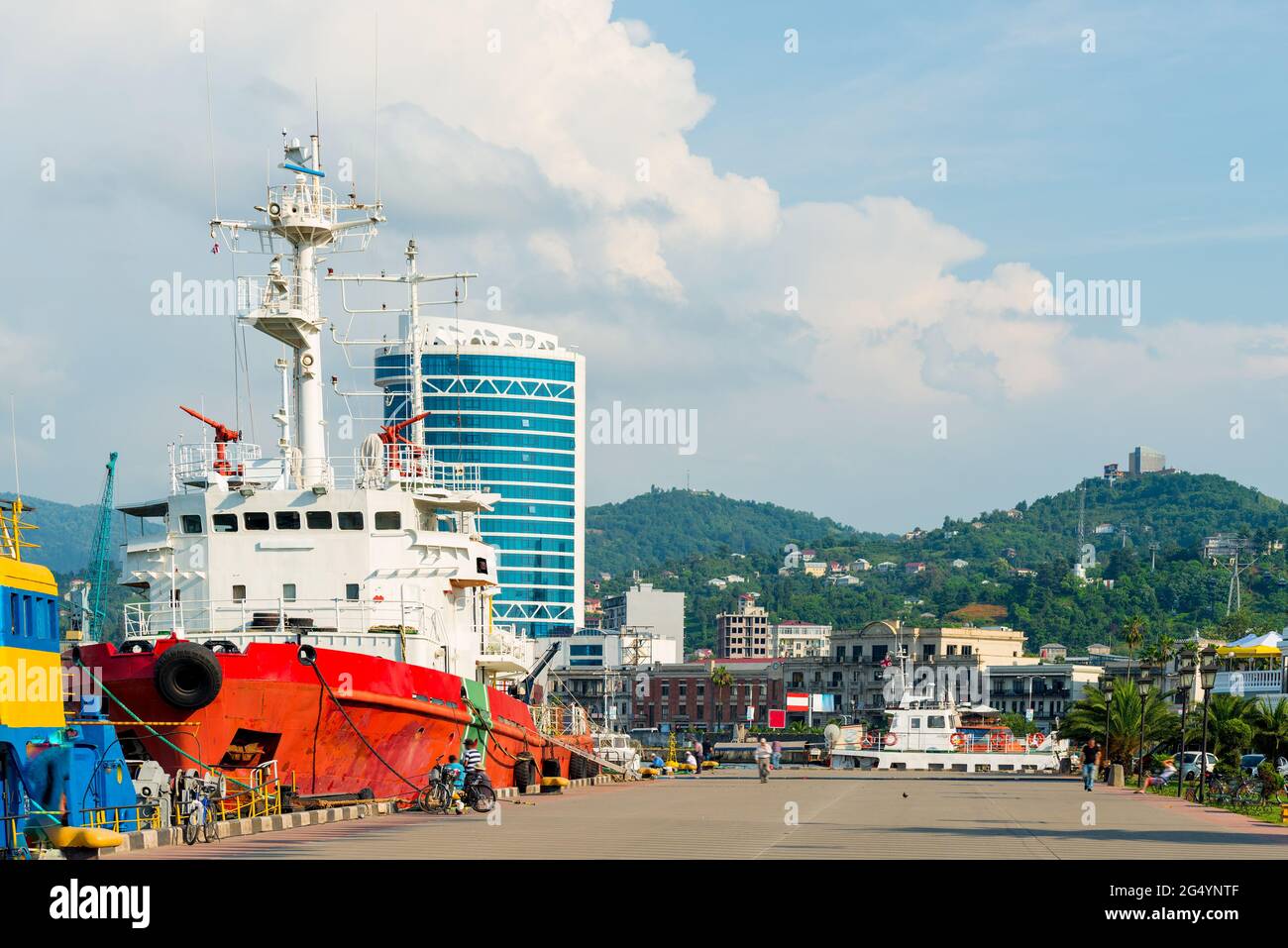 Cargo ship moored in the port of the city against the backdrop of the mountains Stock Photo