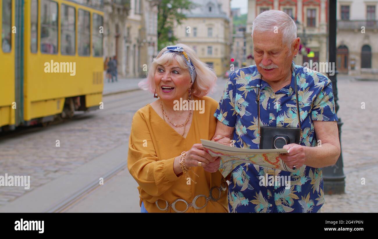 Senior stylish tourists man and woman having a walk and look for way using paper map in old city Stock Photo