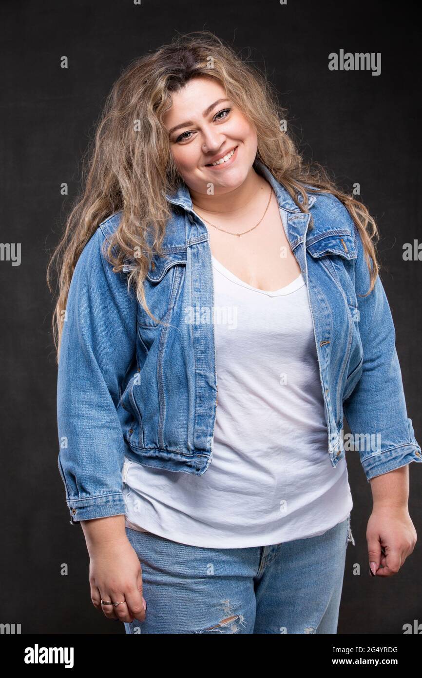 A beautiful fat woman in a denim jacket looks at the camera and smiles