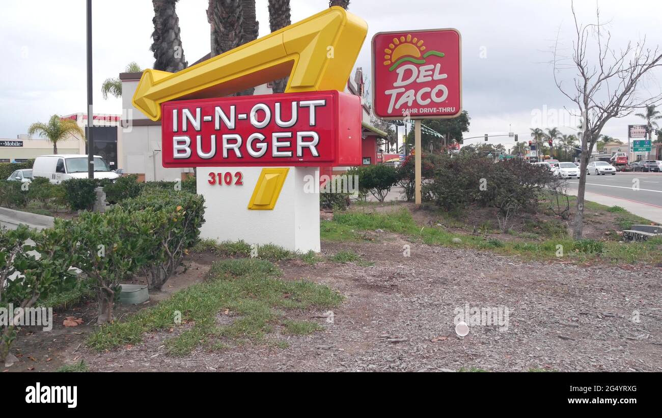 San Diego, California USA - 24 Dec 2020: Fast food restaurants on city street. In-n-out Burger drive thru, Del Taco logo, marketing advertising signs Stock Photo