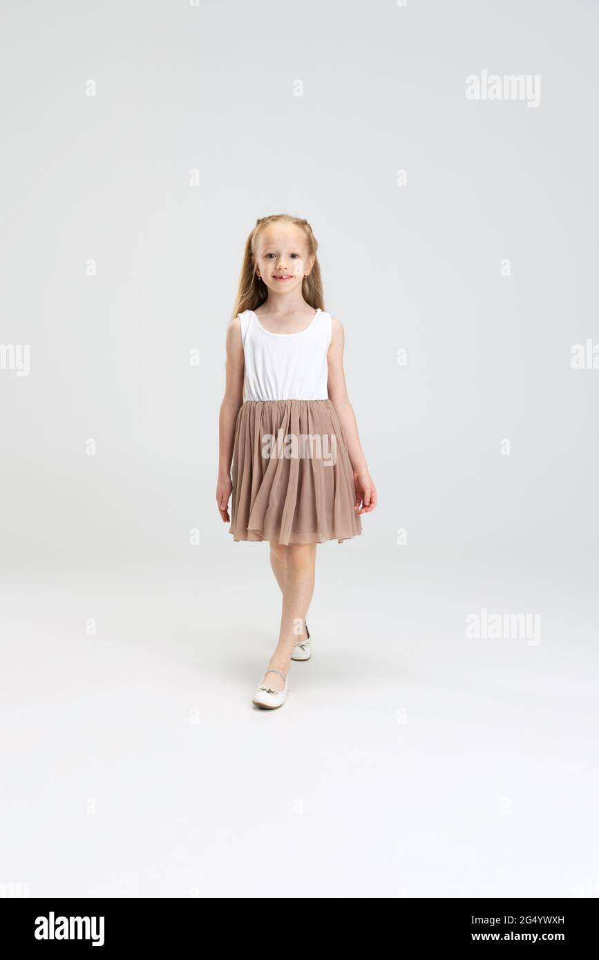 Beautiful little girl in modern stylish dress posing isolated on white ...