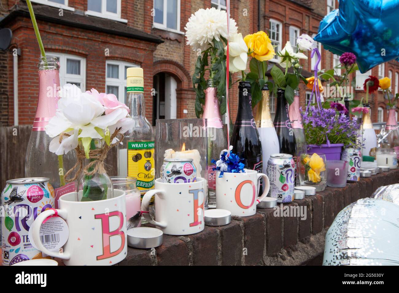 London, UK, 24 June 2021: Tributes line a wall on Bedford Hill in Balham where Mattias Poleon, 27, was shot dead outside his home on 17 June 2021. Tributes include flowers, candles, framed photos, bottles of alcohol and Father's Day balloons. Anna Watson/Alamy Live News. Stock Photo