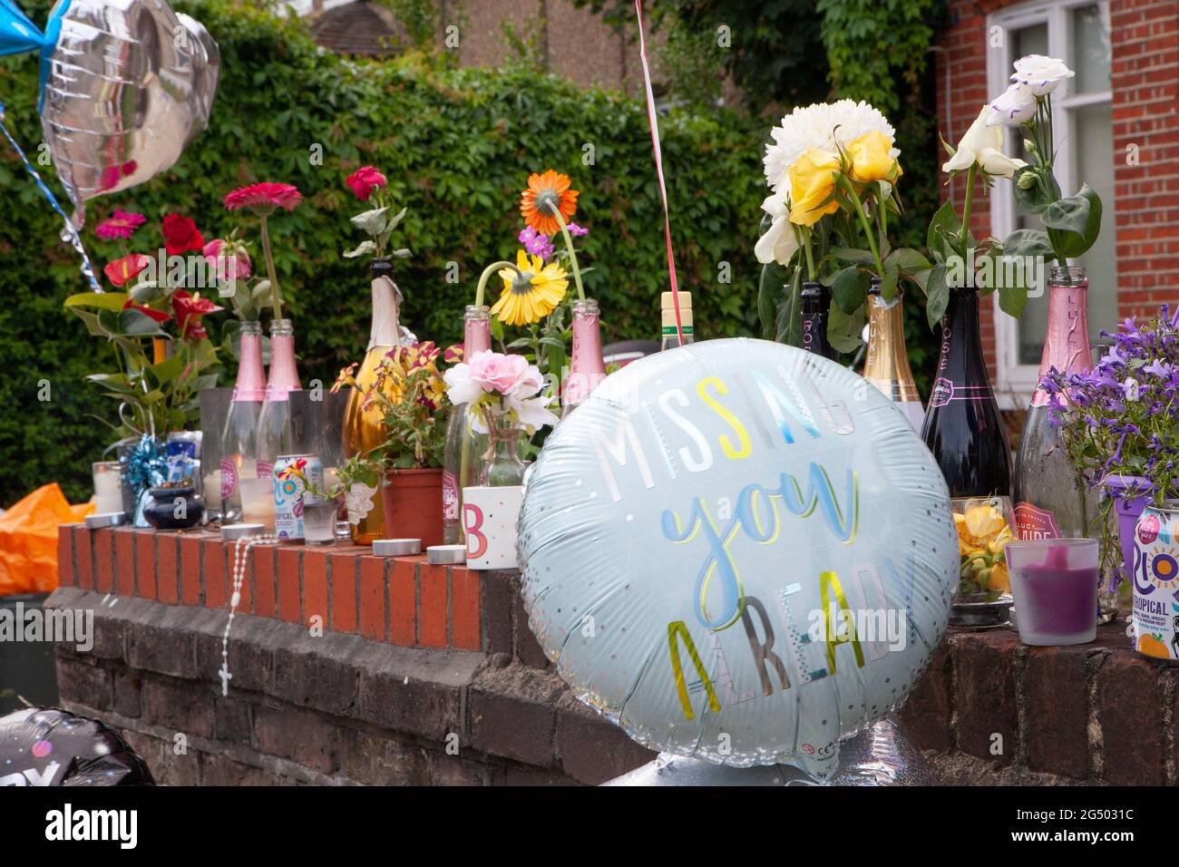 London, UK, 24 June 2021: Tributes line a wall on Bedford Hill in Balham where Mattias Poleon, 27, was shot dead outside his home on 17 June 2021. Tributes include flowers, candles, framed photos, bottles of alcohol and Father's Day balloons. Anna Watson/Alamy Live News. Stock Photo