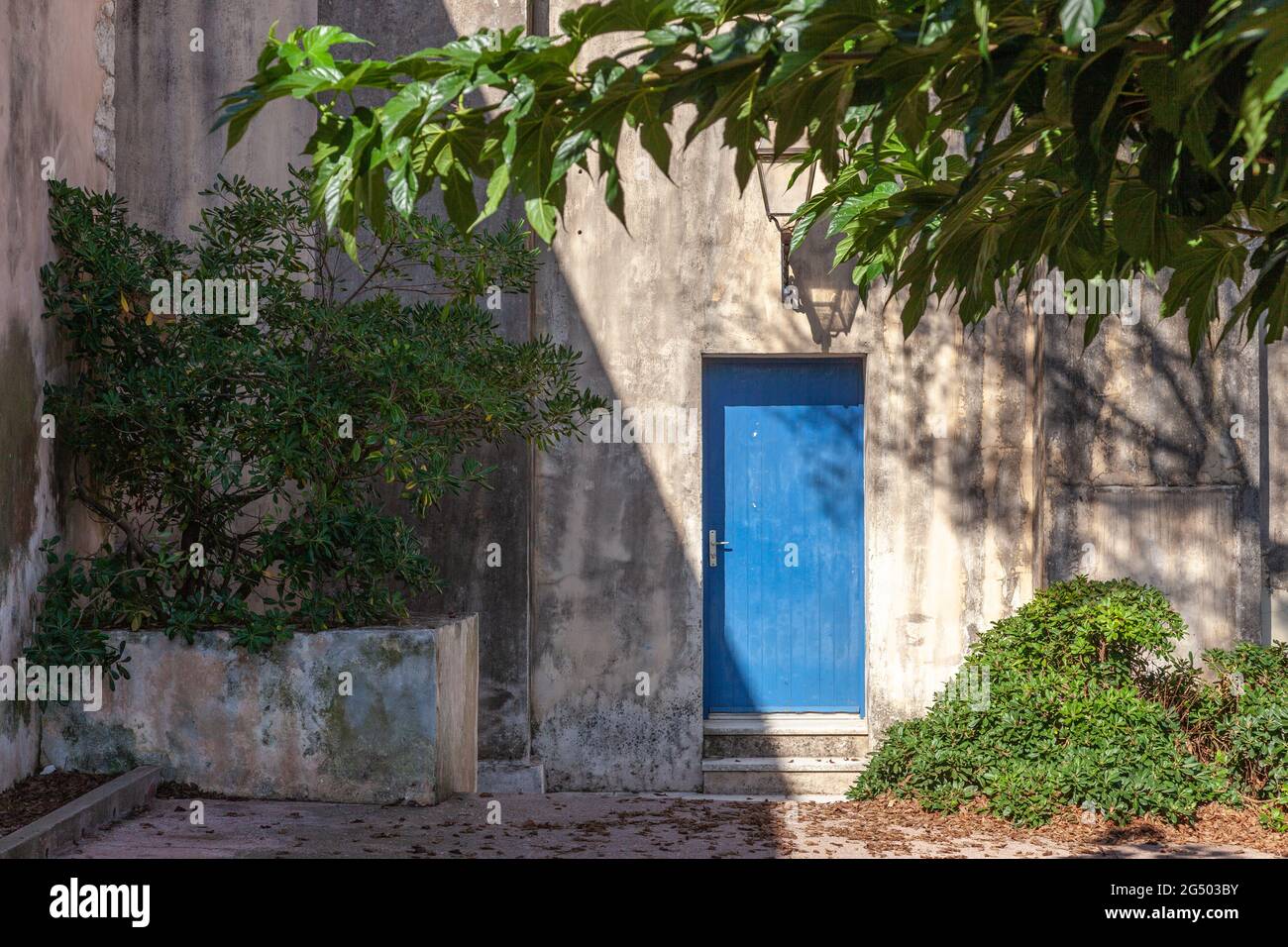 Blue door in a shady courtyard. Gray walls. Bonifacio, Corsica, France Stock Photo