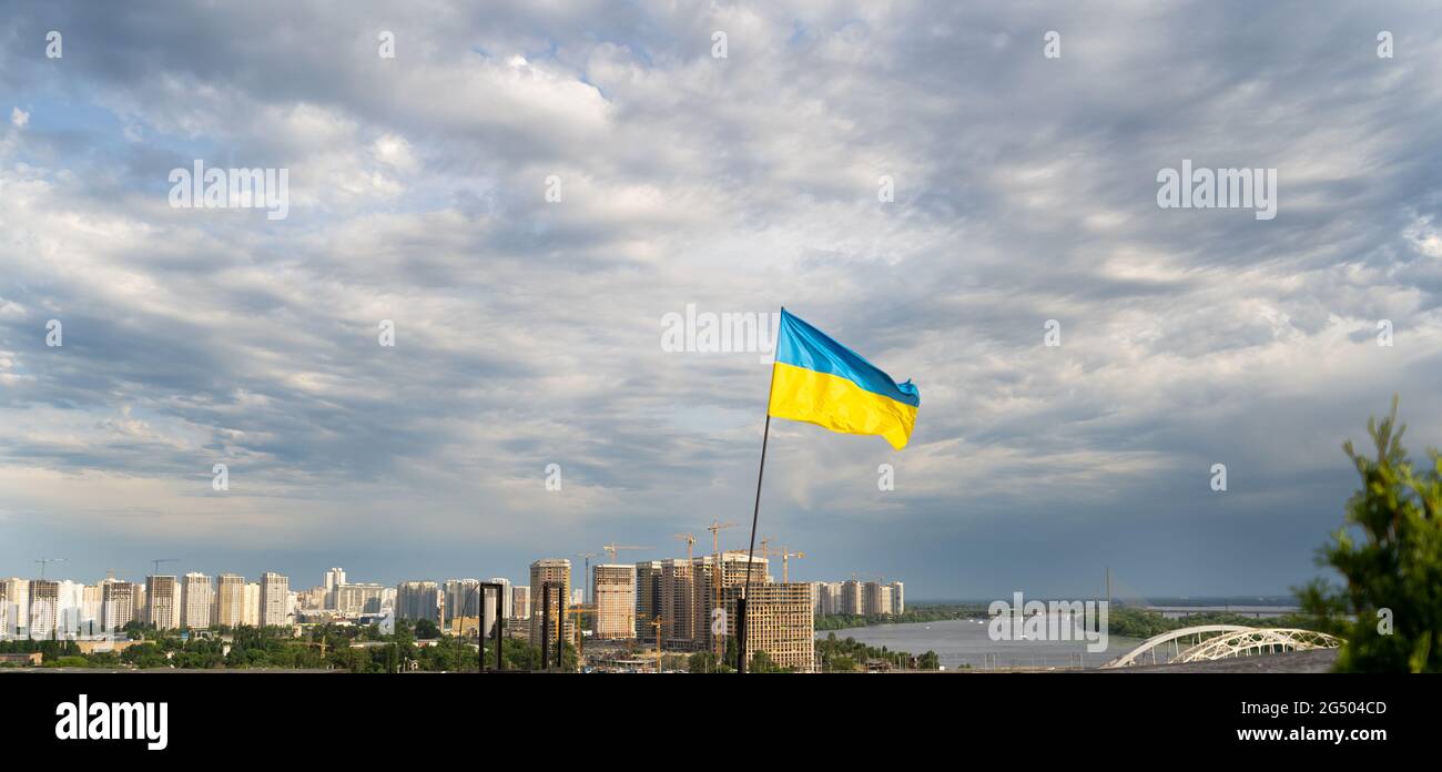 The yellow-blue flag of Ukraine flies in the sky over Kiev and the Dnieper. Beautiful sky. Ukrainian flag. Stock Photo