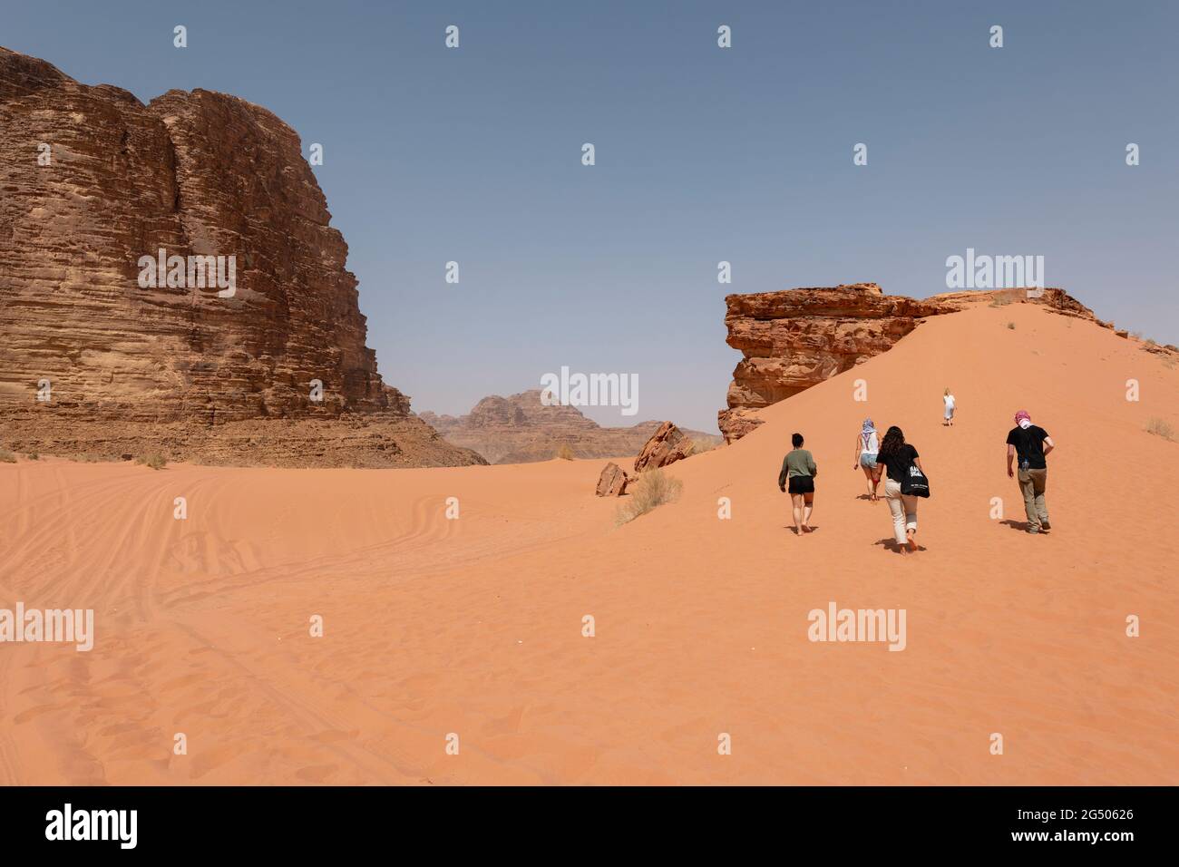 Tourists exploring the Wadi Rum Protected Area. Wadi Rum or Valley of the Moon is famous for its stunning desert landscape, desert valleys and dunes. Stock Photo
