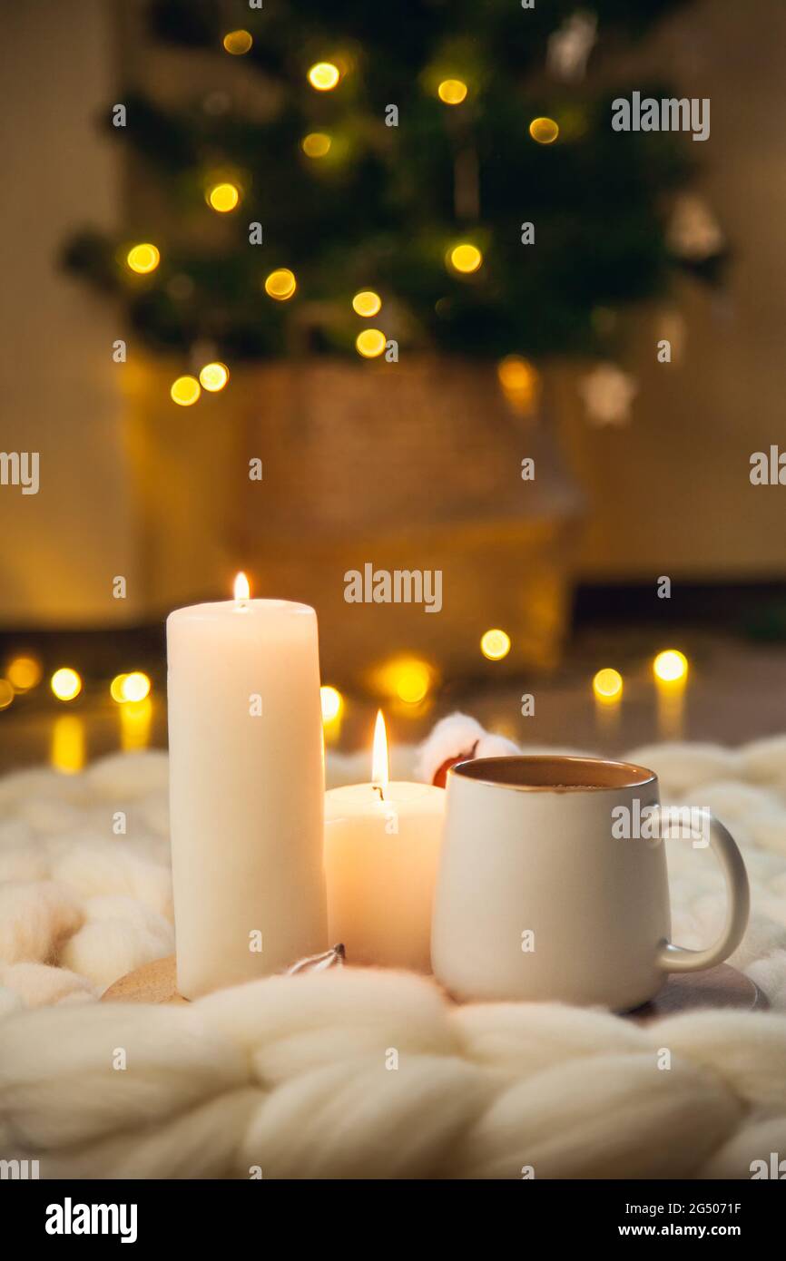 Cup of cappuccino, cookies, and candles on the background of blanket of thick yarn. The atmosphere of homeliness and comfort. Stock Photo
