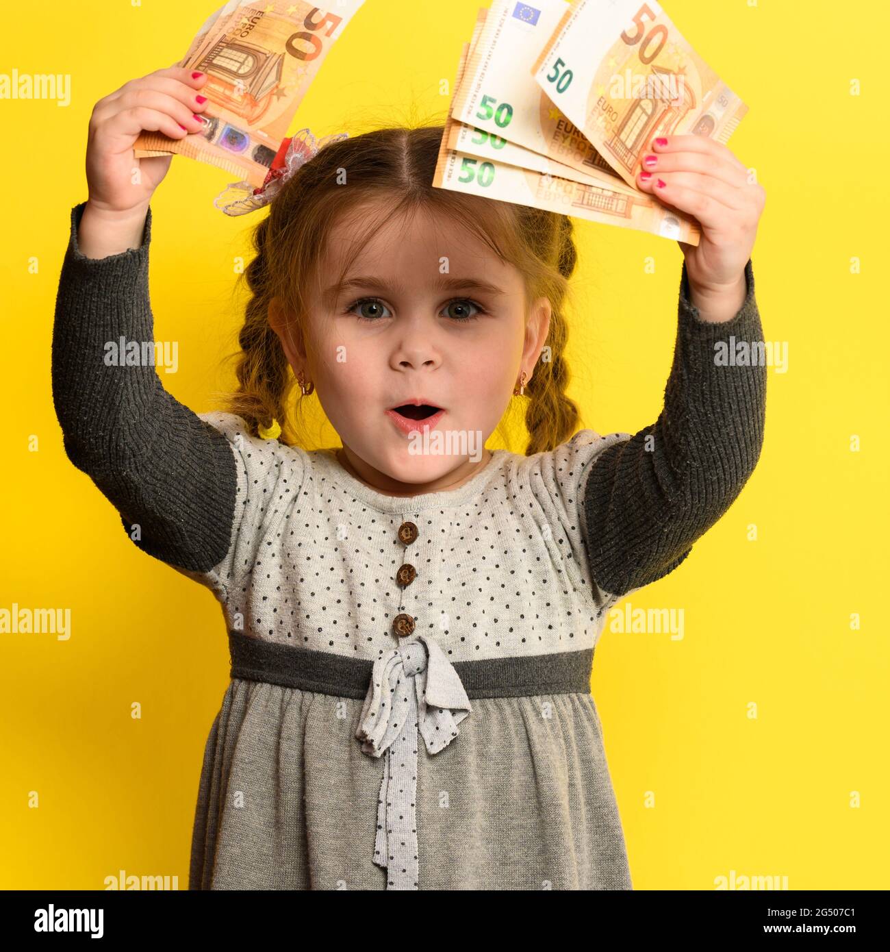 Nonchild saving money in children's hands, yellow background and money with baby Stock Photo