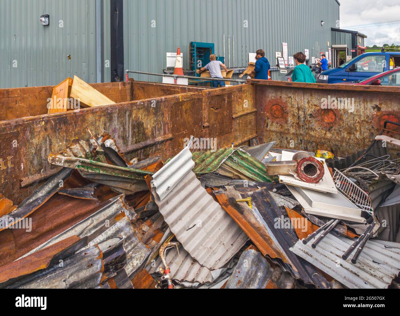 Clonakilty, County Cork, Republic of Ireland.  Eire.  Clonakilty Recycling Centre.  Container full of scrap metal.  People in background deposit cardb Stock Photo
