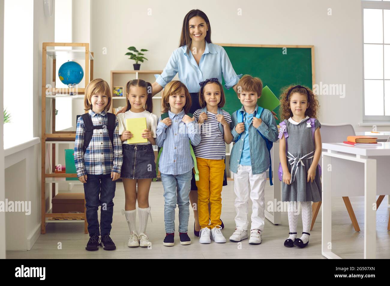 Portrait of happy teacher and little group of elementary students on first day at school Stock Photo