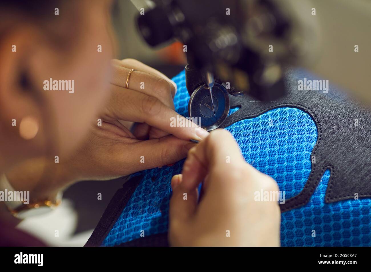 Shoe factory worker using industrial sewing machine to make detail of
